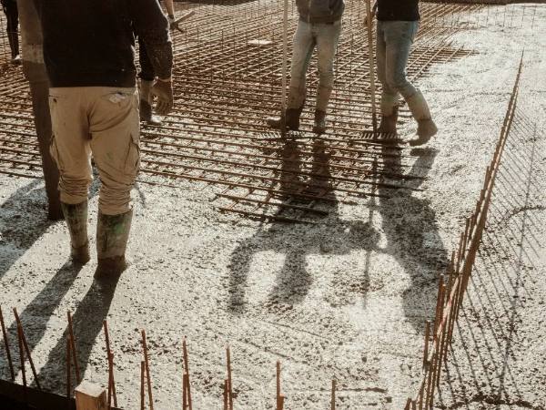 Workers walking on a tied rebar grid while concrete is placed